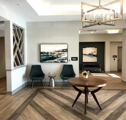 A modern living room with a wooden floor and a large painting on the wall.