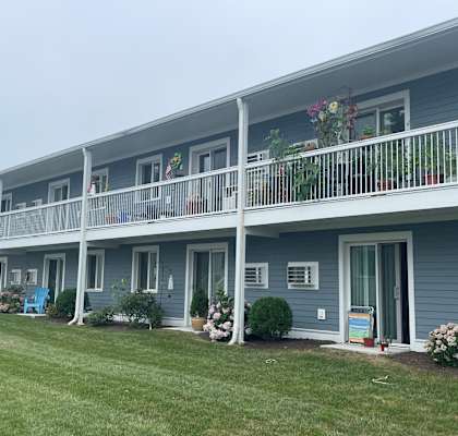 a blue building with a balcony and a grass field