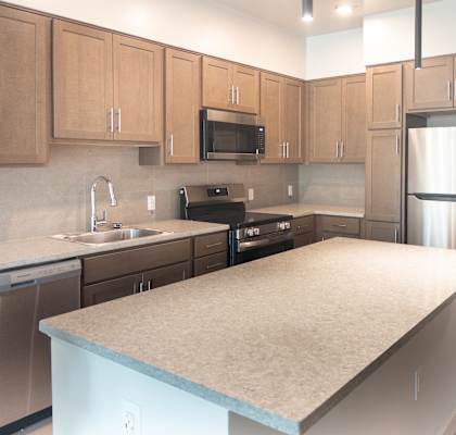 A kitchen with a refrigerator, sink, and microwave.