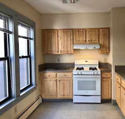 an empty kitchen with white appliances and wooden cabinets