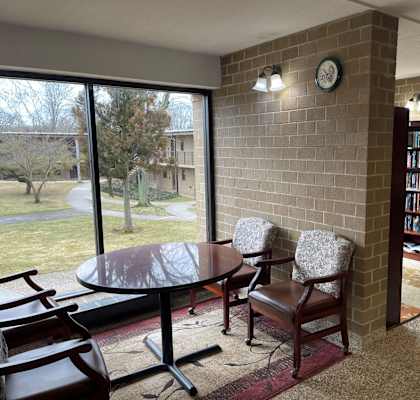 a library with a table and chairs and a large window