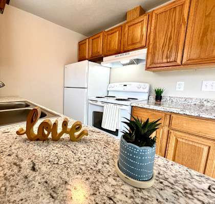 A kitchen with granite countertops and a white fridge.