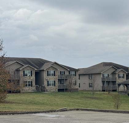 an apartment building on a hill with a cloudy sky