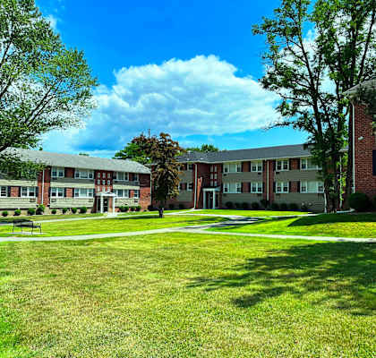 a grassy area with trees and buildings in the background