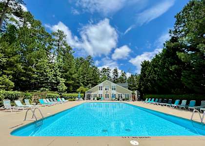 a swimming pool with chaise lounge chairs and a house in the background