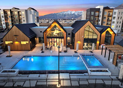 A modern building with a pool in the foreground and snow-capped mountains in the background.