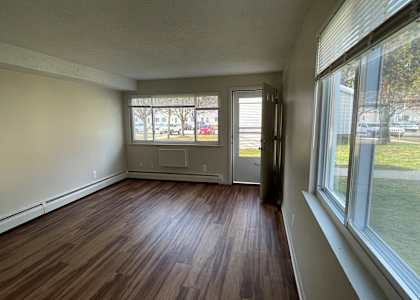 an empty living room with hardwood floors and large windows