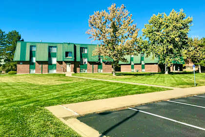 a green building with a lawn and trees in front of it