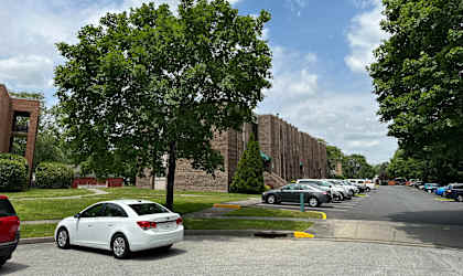a row of cars parked in a parking lot in front of a building