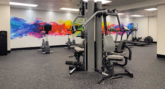 A gym with a variety of equipment including a weight machine and a bench press.