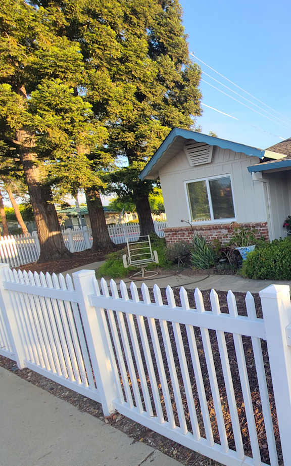 A white house with green shutters and a white picket fence.