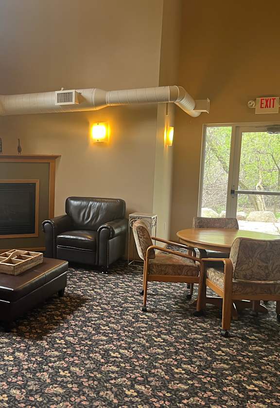 A living room with a black leather couch, a wooden coffee table, and a television.