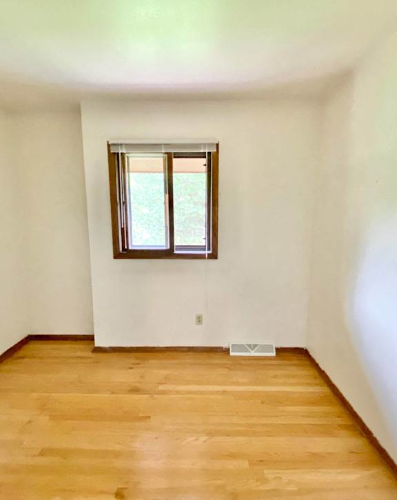 A room with a window and wooden flooring at Root River Apartments, Greendale