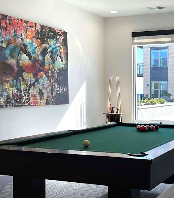 A pool table in a room with a painting on the wall and a window showing an outdoor balcony at 42 Hundred On The Lake, Wisconsin, 53235