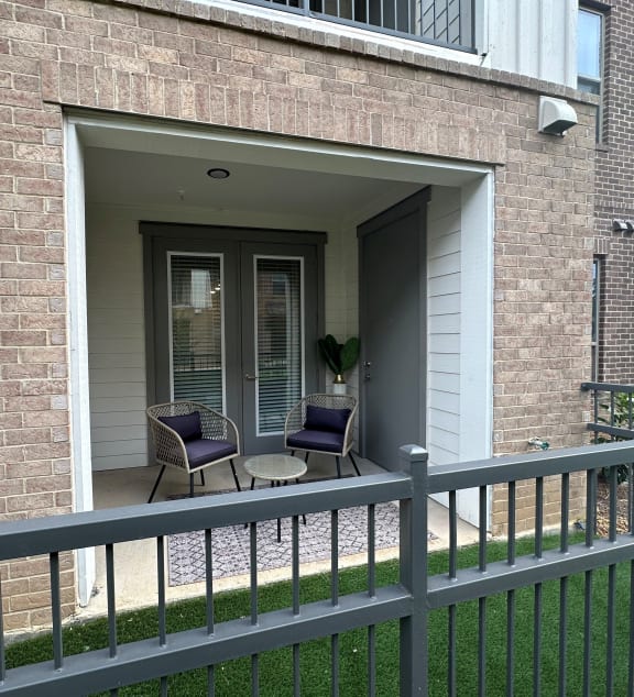a patio with two chairs and a table on a balcony