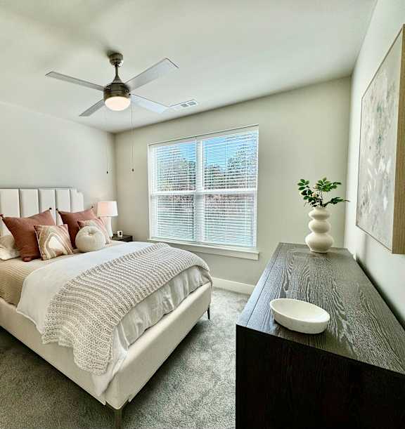 A bedroom with a large bed, a ceiling fan, and a nightstand with a lamp at The Collective Upper Westside Apartments, Atlanta, GA, 30318