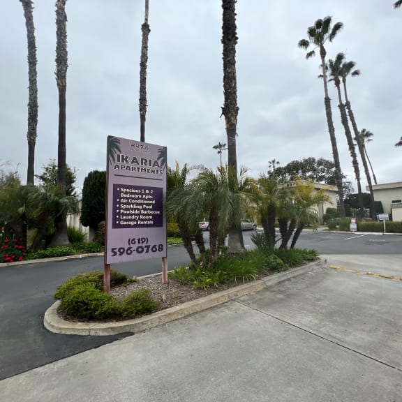a sign in front of a building with palm trees in the background