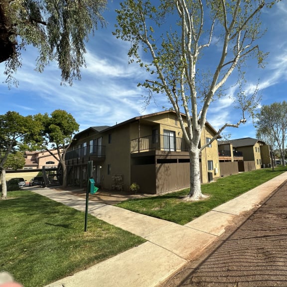 a row of houses with trees in the foreground and a blue sky in the background