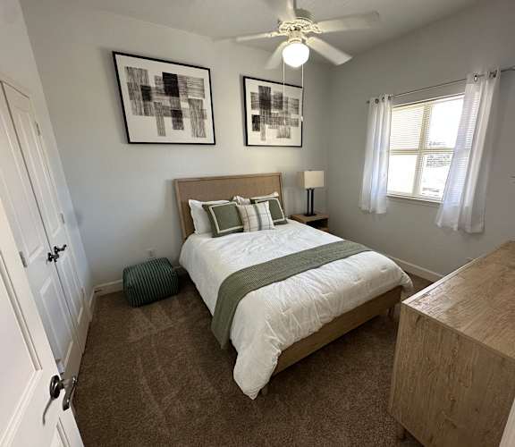 A bedroom with a bed, nightstand, and two pictures on the wall.
