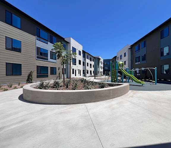 A playground with a slide is in front of a building.