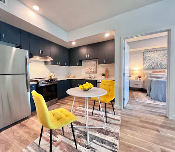 A modern kitchen with a yellow chair and a round table.