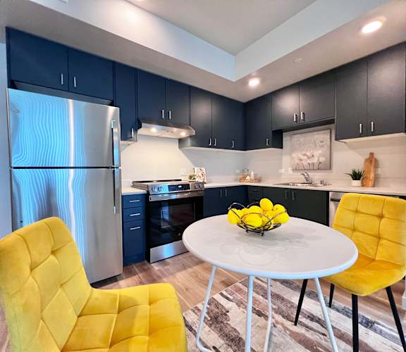 A modern kitchen with a yellow chair and a white table.