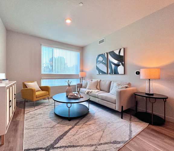 A living room with a yellow chair, a white couch, and a round coffee table.