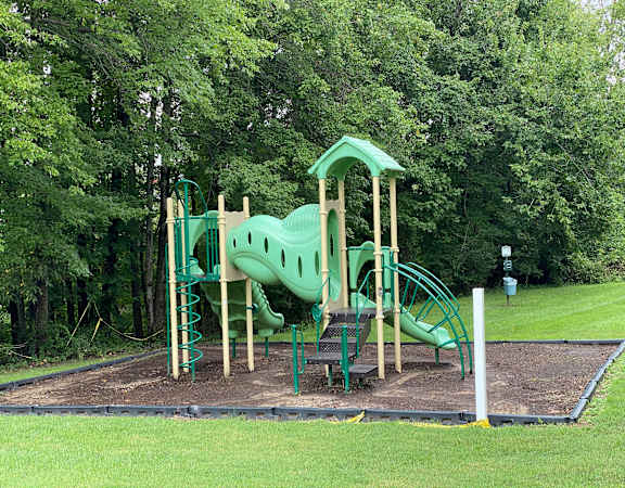 A playground with a green slide and a wooden structure.