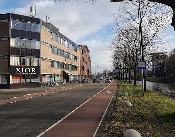 A bike lane is on the right side of a street with a building that says Xtior on the left.