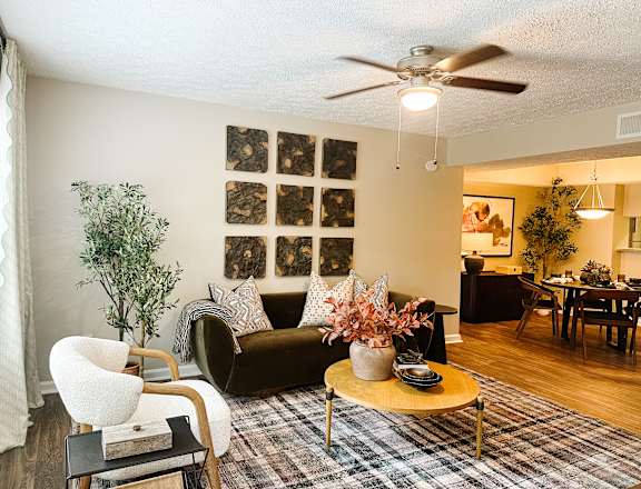 A living room with a couch, chair, and a table with a vase of flowers on it.