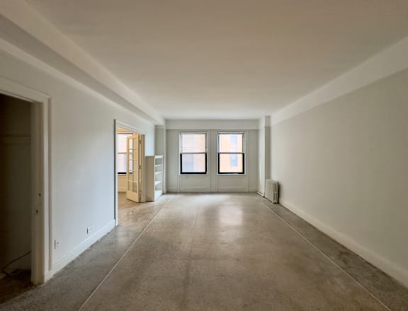 an empty living room with white walls and a door and window