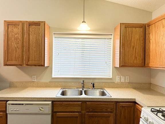 A kitchen with wooden cabinets and a white dishwasher.