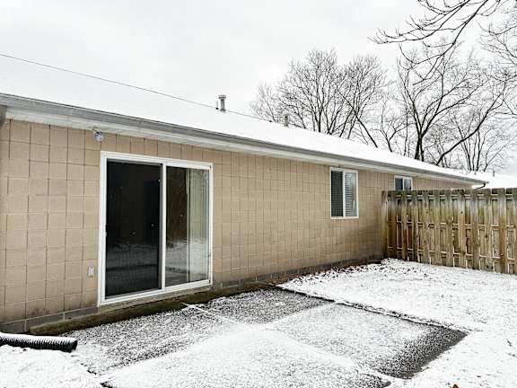 A house with a snow-covered ground and a wooden fence.