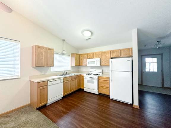 A kitchen with white appliances and wooden cabinets.