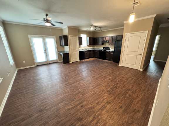 A spacious room with wooden flooring and a ceiling fan.