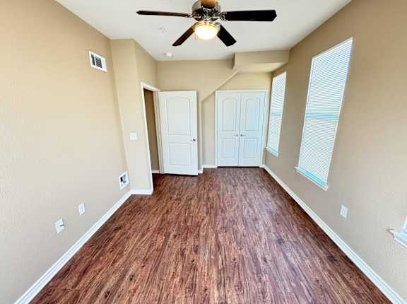 A room with a ceiling fan and wooden flooring.