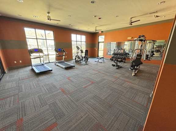 A gym with orange walls and a variety of equipment.