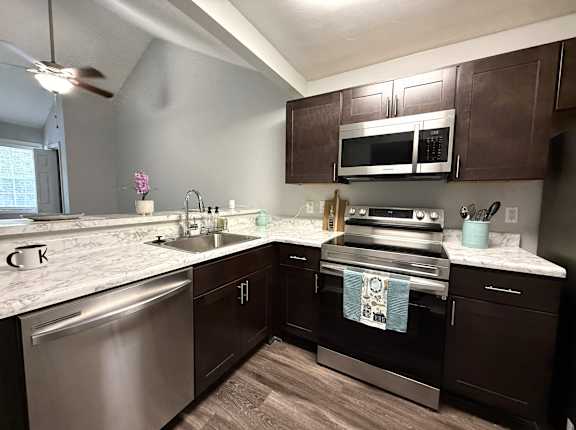 A kitchen with dark brown cabinets and stainless steel appliances.
