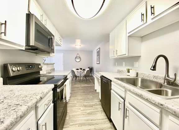 A kitchen with black appliances and white cabinets.