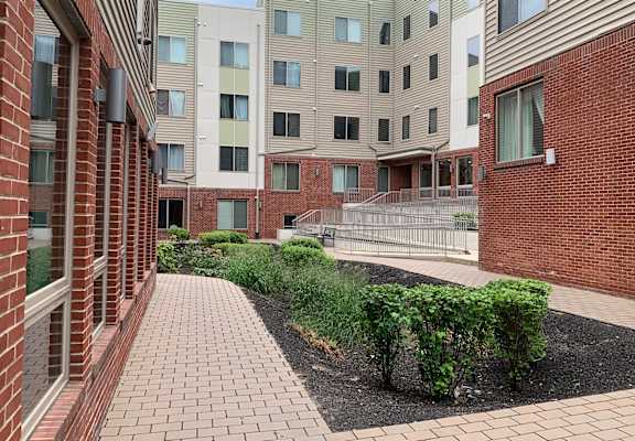 A brick building with a walkway and bushes in front.