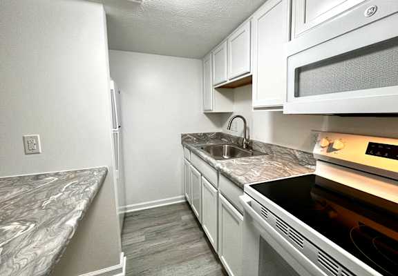 A kitchen with a white refrigerator, microwave, and oven.