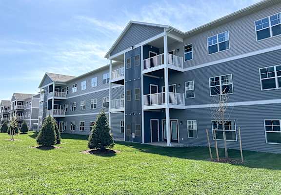 A large apartment complex with multiple balconies and a green lawn in front.