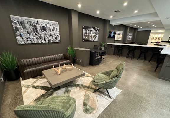 A modern living room with a grey sofa, green armchairs, and a coffee table.