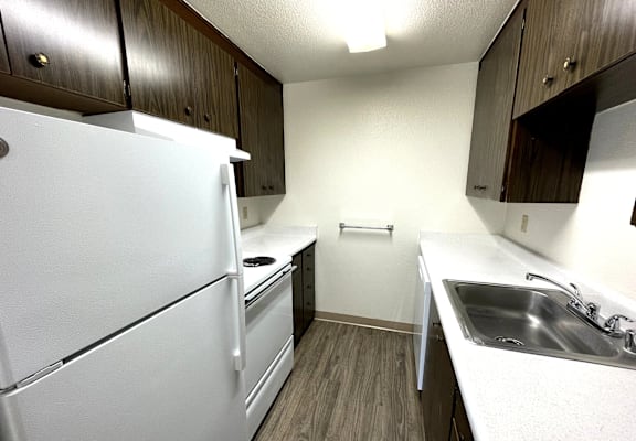 A white refrigerator is in a kitchen with wood cabinets.