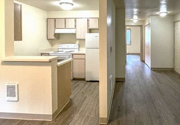 A kitchen with a refrigerator, stove, and cabinets.