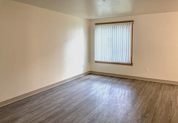 A room with wooden flooring and a window with blinds.