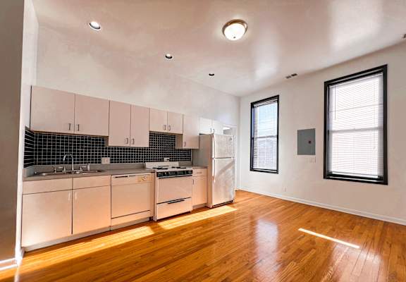 A kitchen with white appliances and wooden floors.