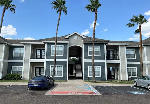 a large apartment building with palm trees in front of it