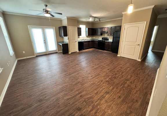 A spacious room with wooden flooring and a ceiling fan.
