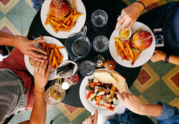 A top view of a group of people sharing a meal with burgers and fries.